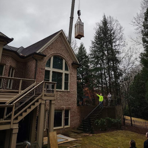 Brick house with a crane lifting a box in the backyard