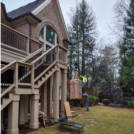 House with a large staircase and deck, with people moving a safe