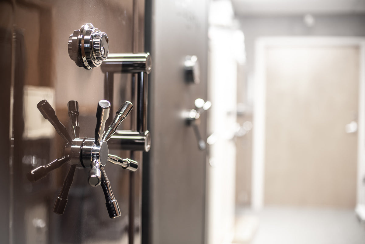 "Close-up of a vault door handle and locking mechanism, with additional safes blurred in the background."