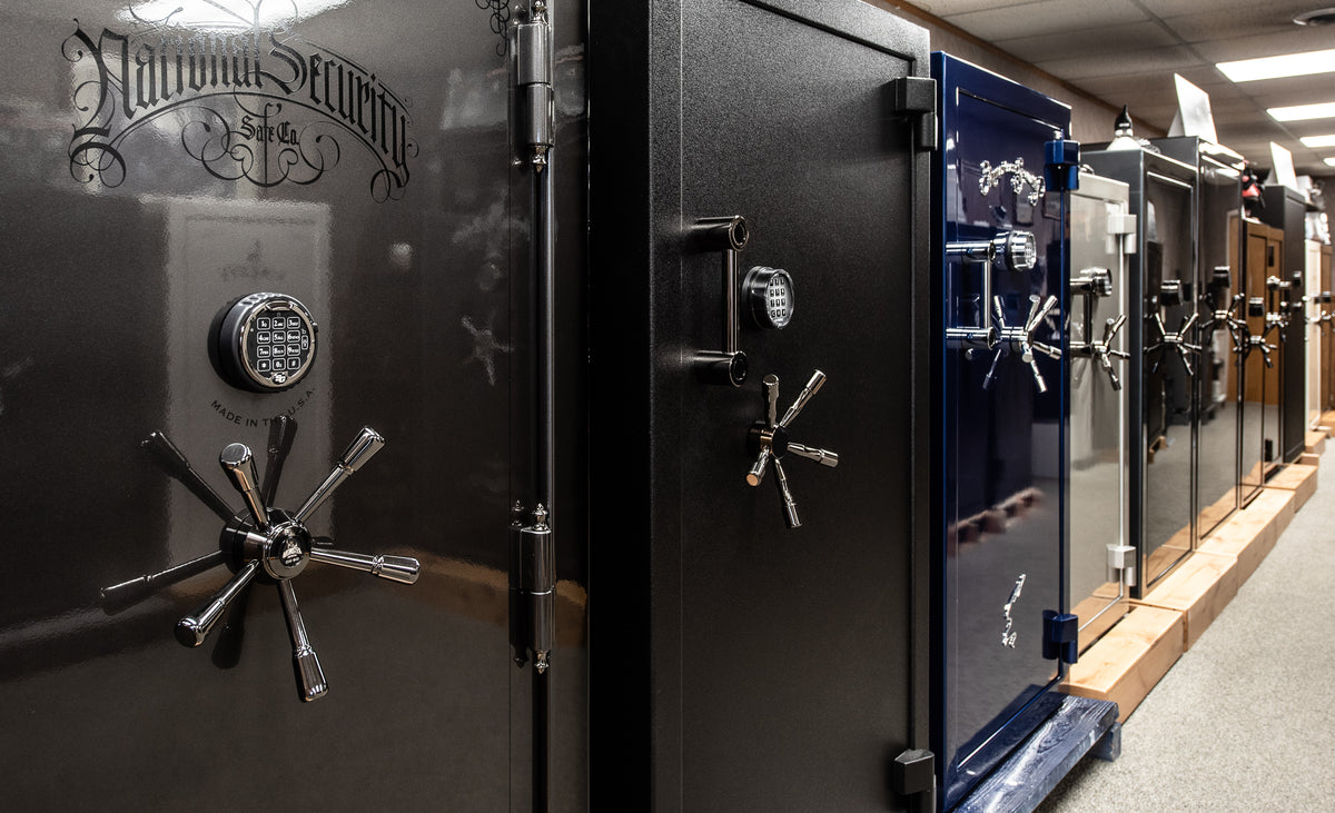 Row of large black safes with various designs in a showroom setting.