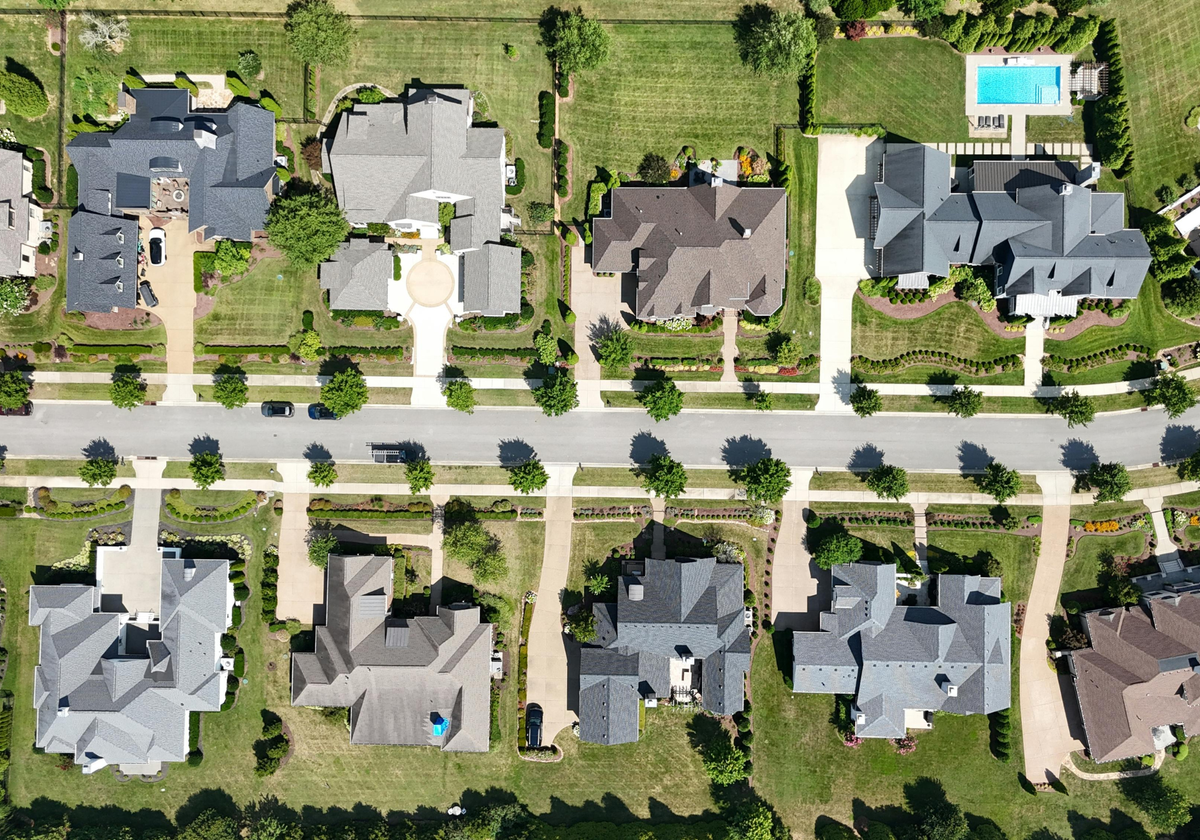 A bird's eye view of a residential neighborhood with houses, roads, and green spaces.
