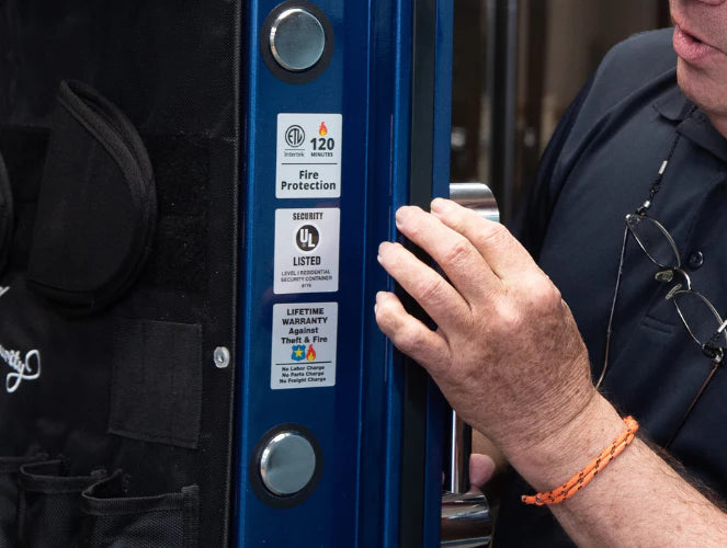 Person opening a blue door with visible labels, wearing a black shirt and orange bracelet.