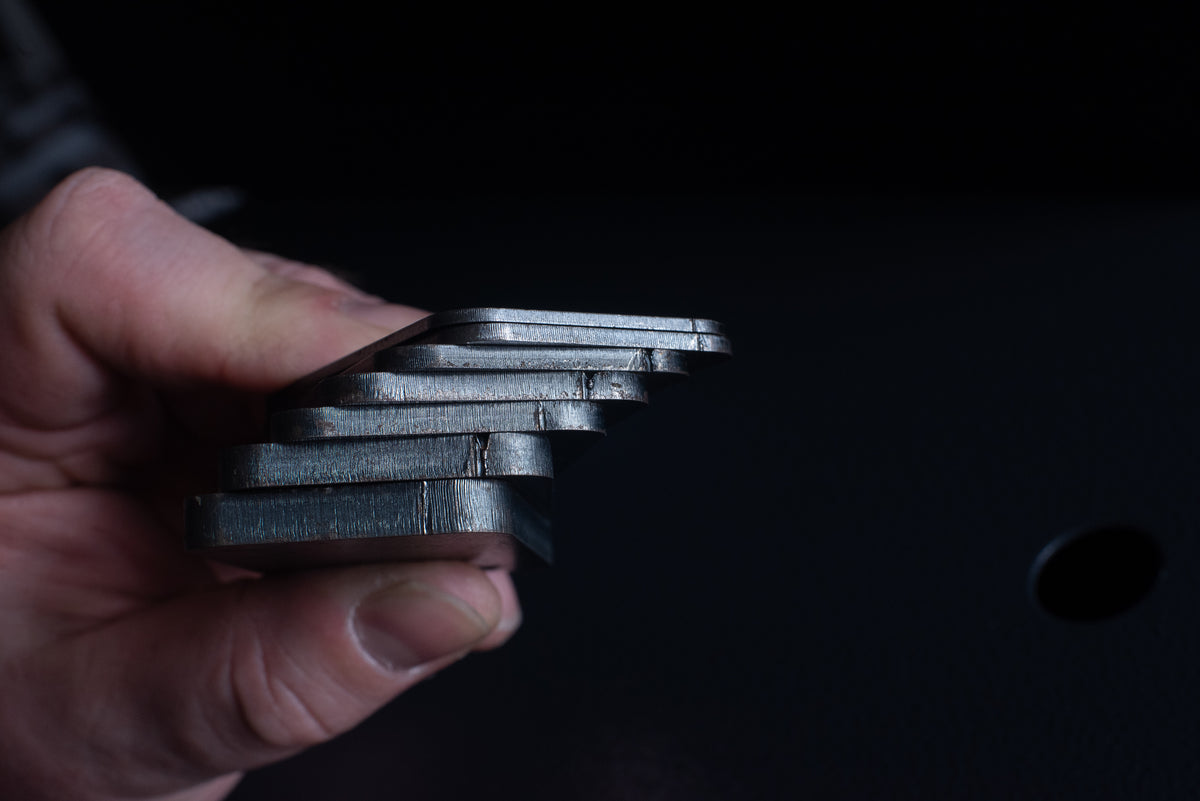 Hand holding a stack of black metal plates against a dark background