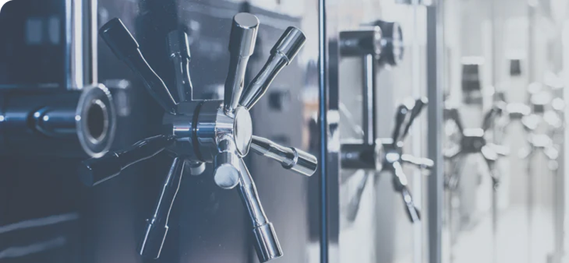 Close-up of chrome safe door handles on a row of safes.