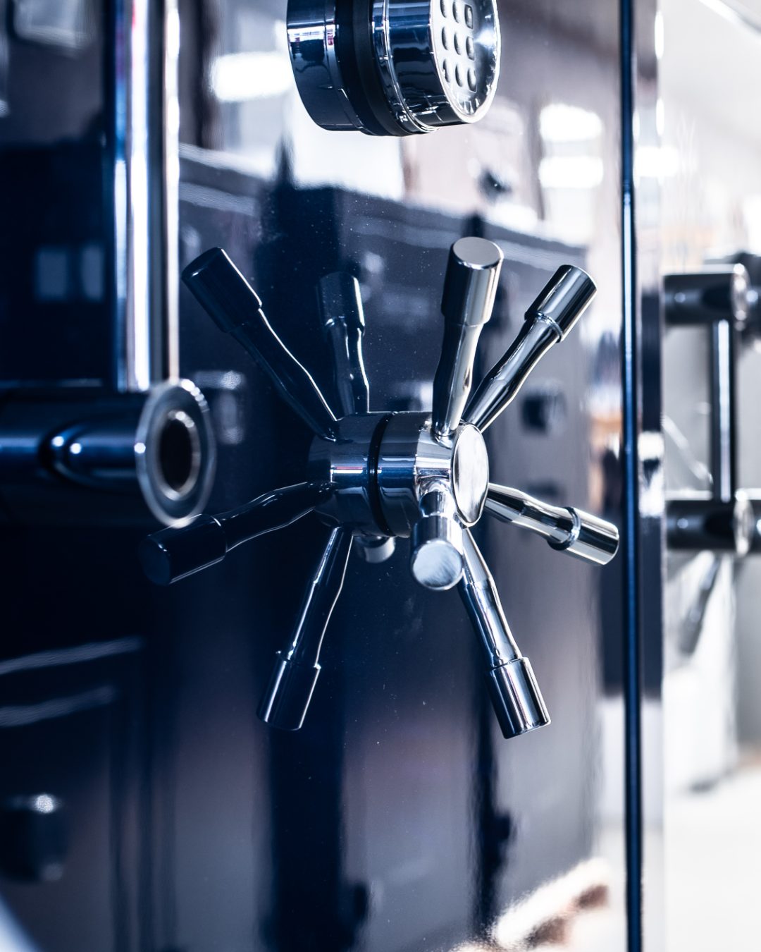 Close-up of a heavy-duty security safe door featuring a multi-spoke chrome combination lock and a digital keypad entry system.