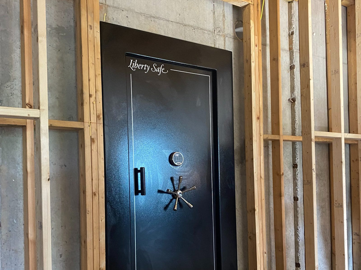 A black Liberty Safe home security safe installed in an unfinished wooden wall frame structure.